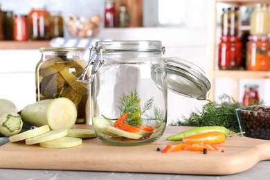 Jar with zucchini and dill on grey marble table indoors. Pickling vegetables
