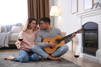 Happy couple spending time together near fireplace at home