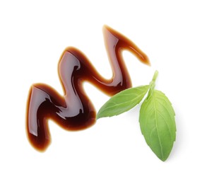 Photo of Balsamic glaze and basil leaves on white background, top view