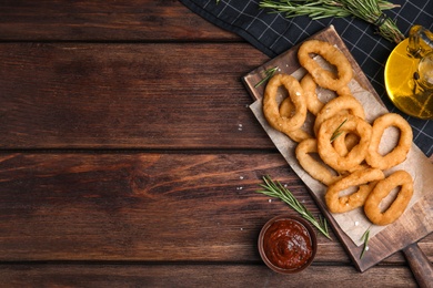 Fried onion rings served on wooden table, flat lay. Space for text