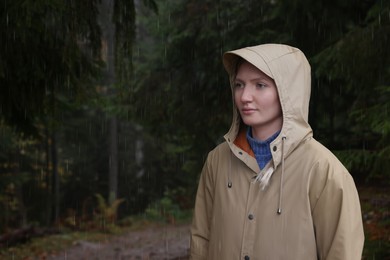 Young woman with raincoat in forest under rain