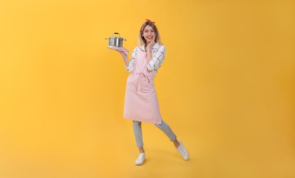 Young housewife with pot on yellow background