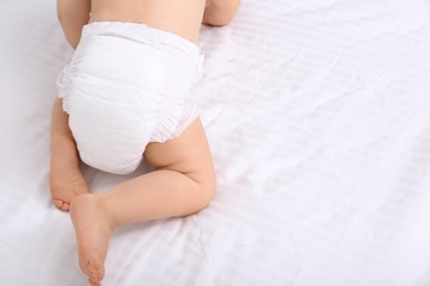 Back view of cute baby in dry soft diaper on white bed, closeup. Space for text