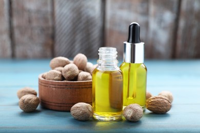 Bottles of nutmeg oil and nuts on turquoise wooden table