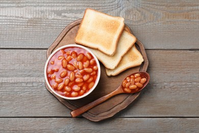 Toasts and delicious canned beans on wooden table, top view