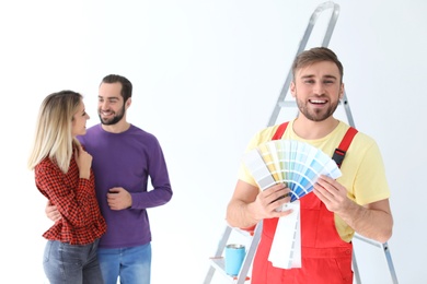 Male decorator and young couple with color palette on white background