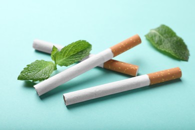 Menthol cigarettes and mint on turquoise background