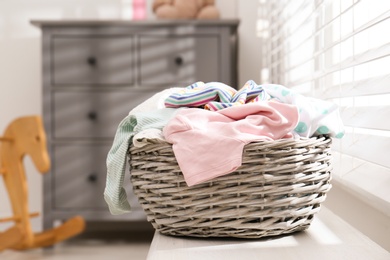 Wicker laundry basket with different clothes on window sill indoors