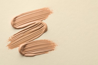 Samples of liquid skin foundations on beige background, top view. Space for text