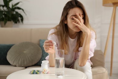 Woman putting medicine for hangover into glass of water at home