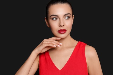 Photo of Portrait of young woman wearing beautiful red lipstick on black background