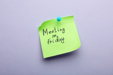 Paper note with words Meeting on Friday pinned to light grey background