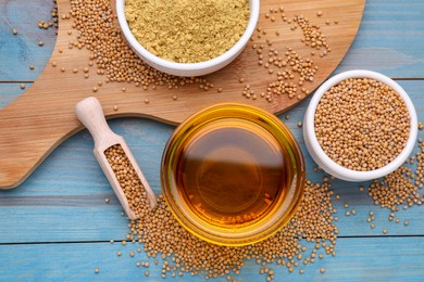 Photo of Bowl of natural oil, mustard seeds and powder on light blue wooden table, flat lay