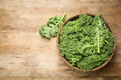 Fresh kale leaves on wooden table, top view. Space for text