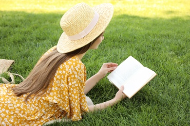 Young woman reading book on green grass
