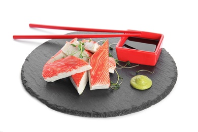 Slate plate with fresh crab sticks and soy sauce on white background