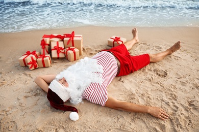 Santa Claus with presents relaxing on beach. Christmas vacation