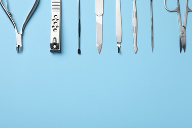 Photo of Set of manicure tools on light blue background, flat lay. Space for text