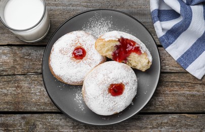 Delicious jelly donuts served with milk on wooden table, flat lay