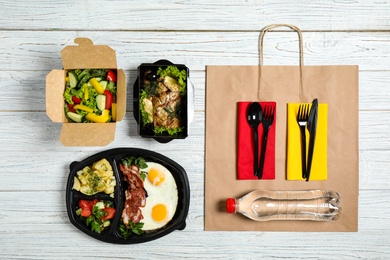 Lunchboxes with different meals on white wooden table, flat lay. Healthy food delivery