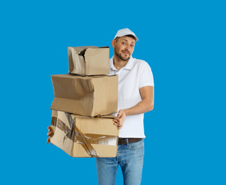 Emotional courier with damaged cardboard boxes on blue background. Poor quality delivery service