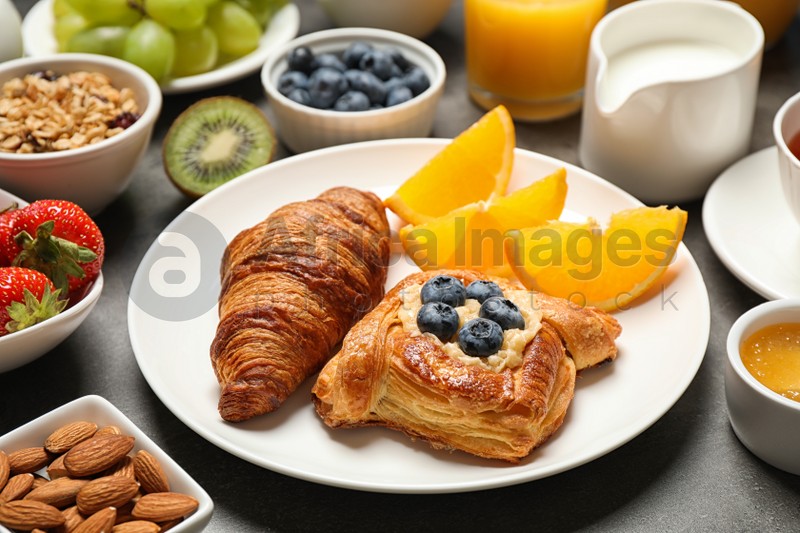 Photo of Delicious pastries and orange slices on grey table, closeup. Buffet service