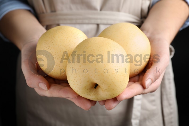 Photo of Woman holding ripe apple pears on black background, closeup