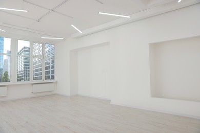 Empty office room with white walls, clean window and modern lights on ceiling. Interior design