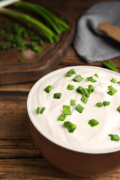 Fresh sour cream with onion on wooden table, closeup