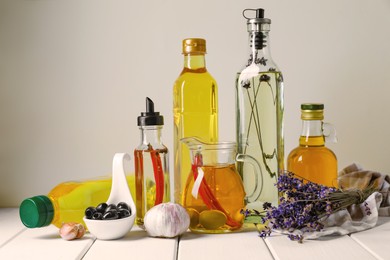 Photo of Different cooking oils and ingredients on white wooden table against light background
