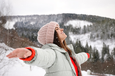 Happy woman against snowy mountains. Winter vacation