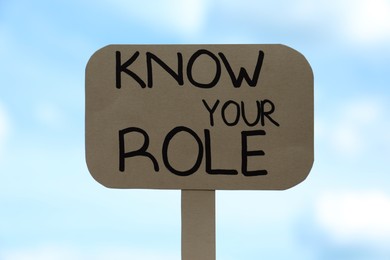 Photo of Cardboard sign with phrase Know Your Role against cloudy sky