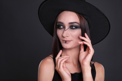 Mysterious witch wearing hat on black background, closeup