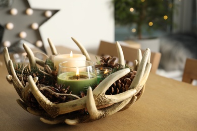 Burning scented conifer candles with Christmas decor  on wooden table indoors