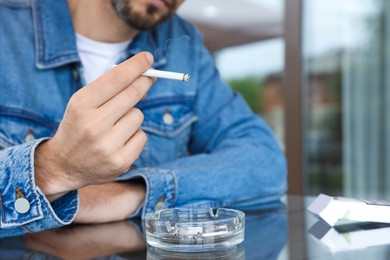 Photo of Man smoking cigarette at table in outdoor cafe, closeup