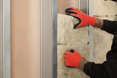Photo of Worker installing thermal insulation material on wall, closeup
