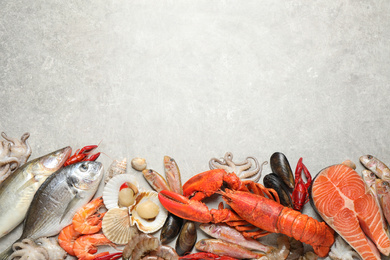 Fresh fish and different seafood on light grey table, flat lay. Space for text