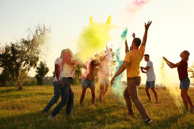 Photo of Happy friends having fun with colorful powder dyes outdoors. Holi festival celebration