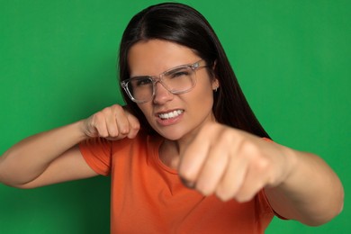 Young woman ready to fight on green background