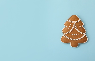 Photo of Christmas tree shaped gingerbread cookie on light blue background, top view. Space for text