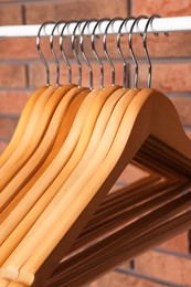 Wooden clothes hangers on rail near red brick wall, closeup