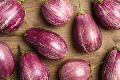 Photo of Raw ripe eggplants on wooden table, flat lay