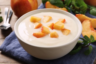 Delicious yogurt with fresh peach on wooden table, closeup