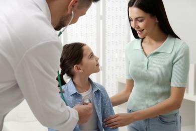 Mother with daughter visiting pediatrician in hospital. Doctor examining little girl