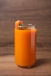 Photo of Fresh carrot juice in glass on wooden table