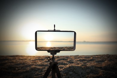 Taking photo of beautiful seascape with smartphone mounted on tripod