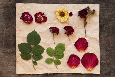 Photo of Paper with beautiful flowers, leaves and petals prepared for drying on table, flat lay