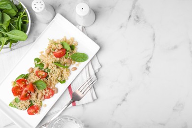 Photo of Delicious quinoa salad with tomatoes, beans and spinach leaves served on white marble table, flat lay. Space for text