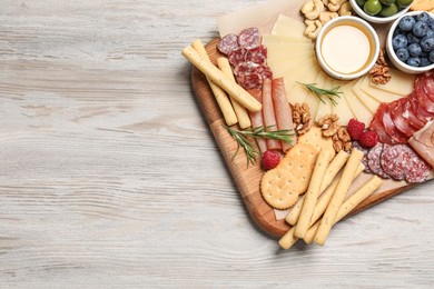 Tasty parmesan cheese and other different appetizers on white wooden table, top view. Space for text