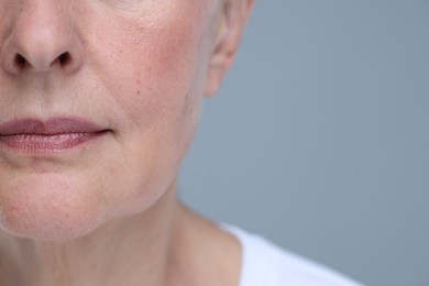 Photo of Senior woman with aging skin on grey background, closeup and space for text. Rejuvenation treatment